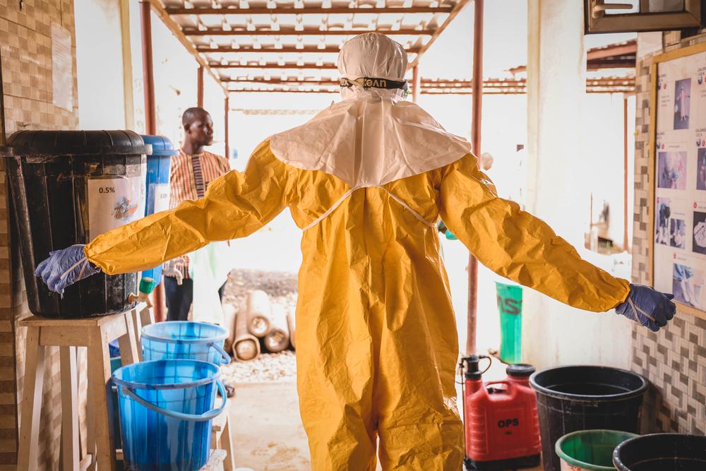 Un médecin international de MSF lève les mains de côté alors qu'il est aspergé d'eau diluée au chlore après une tournée dans l'unité de virologie du Federal Teaching Hospital Abakaliki 1, dans l'État d'Ebonyi. © MSF/Abba Adamu Musa