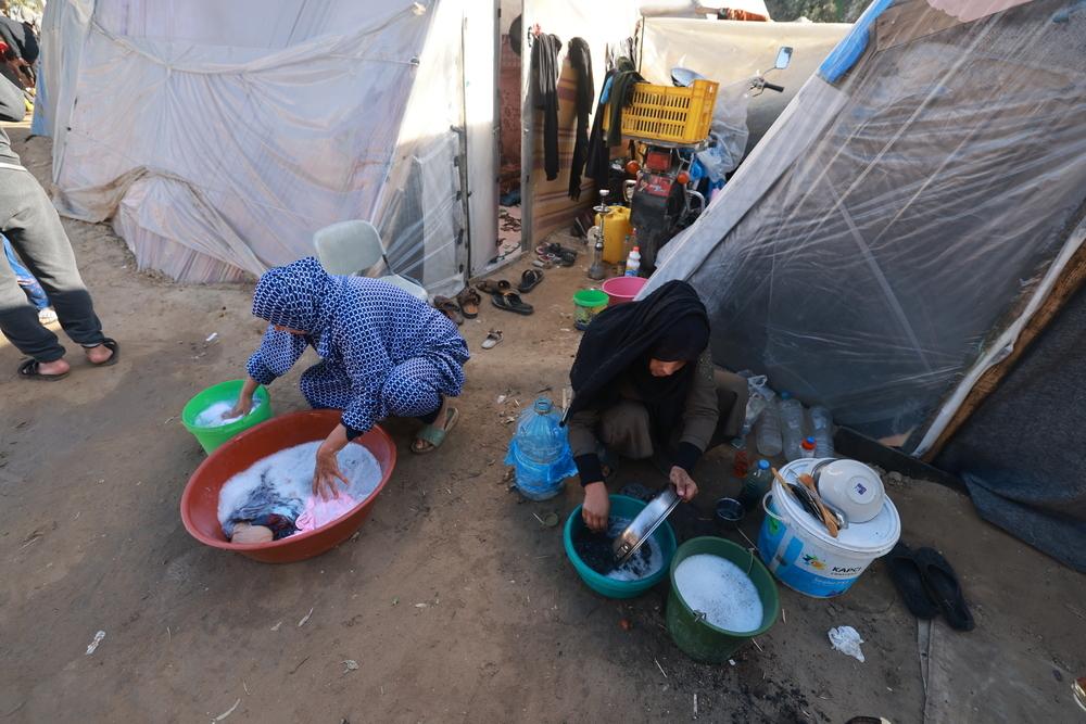 Des femmes palestiniennes déplacées lavent des vêtements et de la vaisselle dans des seaux à l'extérieur de leurs tentes dans le quartier Al-Shaboura de la ville de Rafah, au sud de Gaza. ©Mohammed Abed