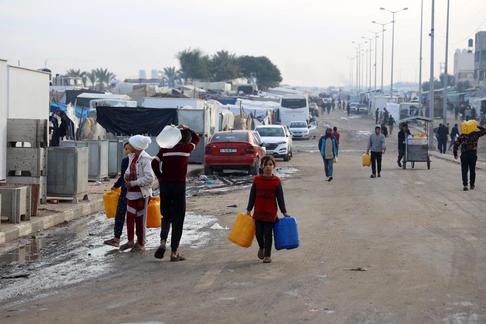 Des hommes et des enfants palestiniens portent des bouteilles d'eau à Tal Al-Sultan, un quartier de la ville de Rafah, dans le sud de la bande de Gaza. ©Mohammed Abed