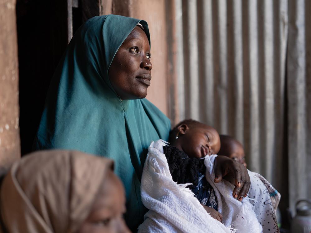 Maryam Umar, connue dans la communauté sous le nom de Mama Yousef, berce l'une de ses jumelles qui a survécu à la rougeole. © Georg Gassauer/MSF