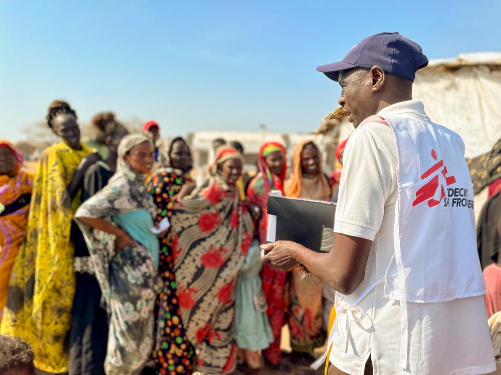 Un membre du personnel de MSF explique aux réfugiés et aux rapatriés les étapes à suivre au poste frontière de Joda, entre le Sud-Soudan et le Soudan, avant d'être transférés au centre de transit de Renk. Mars, 2024 © Kristen Poels/MSF