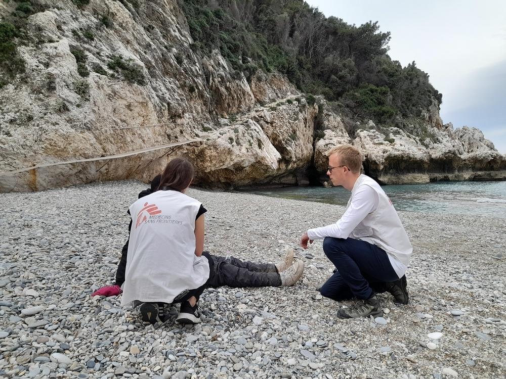 Une équipe MSF apporte des premiers soins médicaux et psychologiques à un homme qui vient d'arriver sur une plage isolée de Samos. L'homme est assis sur le sol, reprenant son souffle, pendant que le médecin l'examine. Grèce, mars 2024  © Myrto Mouzaki/MSF