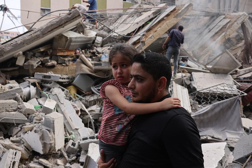 A man carries a child through the devastation in Gaza./ MSF