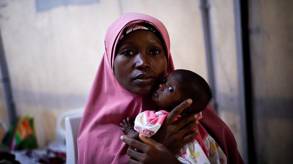 Maryam Abubakar, assise avec l'un de ses jumeaux dans la tente de débordement de l'hôpital MSF de Nilefa Keji à Maiduguri, au Nigéria. Ses deux jumeaux ont été diagnostiqués comme souffrant de malnutrition aiguë sévère (MAS). Juin, 2024 © Georg Gassauer/MSF