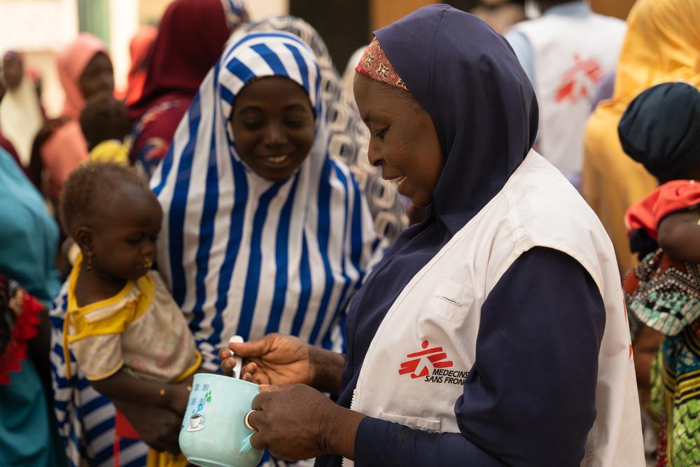 Maryam Muhammad, superviseur MSF de la promotion de la santé à Kebbi, donne une cuillère de Tom Brown à un enfant lors d'une démonstration de recettes dans le village de Maishaka, dans l'État de Kebbi, au nord-ouest du Nigeria. Une centaine de femmes ont participé à cette démonstration. ©Georg Gassauer/MSF 