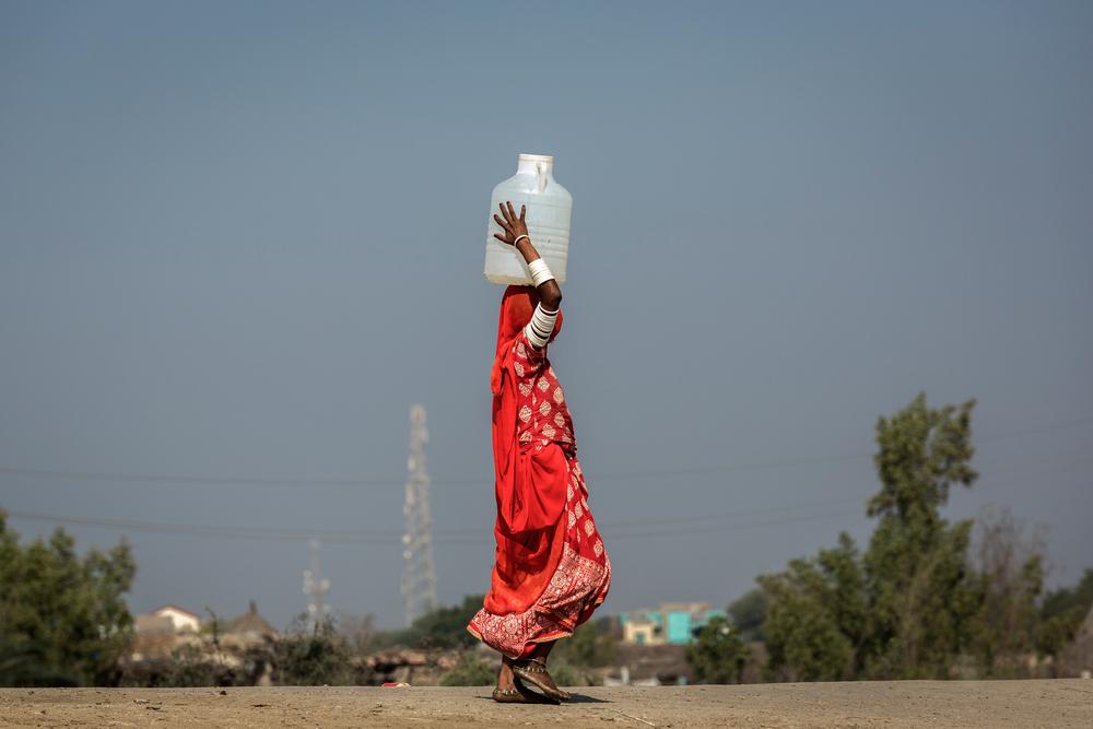 Une femme vêtue d'une robe traditionnelle porte sur sa tête un bidon d'eau potable collecté par le camion-citerne de MSF arrivé à Khipro, dans la province de Sindh au Pakistan