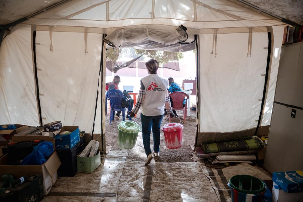 Un membre de l’équipe MSF transporte des seaux contenant des kits remis à chaque patient qui vient se faire soigner pour la diphtérie