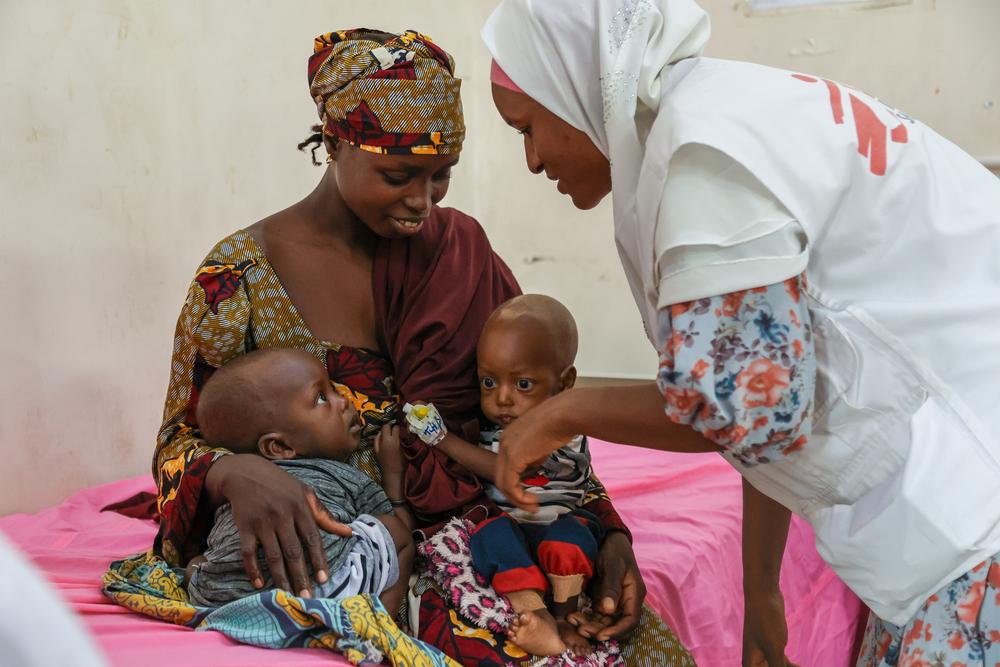 Une mère et ses deux jumeaux, assistés par un membre du personnel MSF.