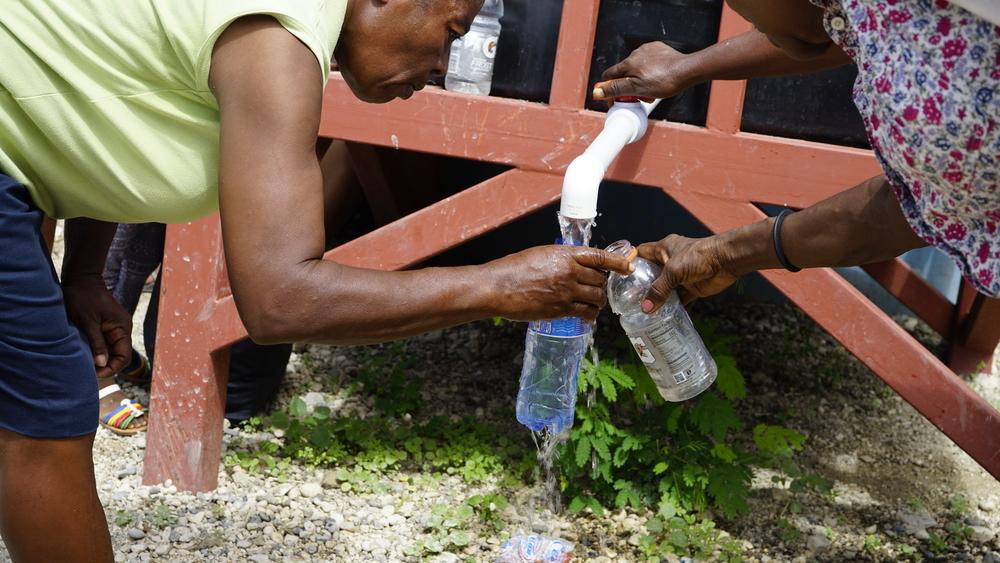 Des personnes remplissent leurs bouteilles à partir d'un réservoir dans un camp de personnes déplacées à Port-au-Prince, en Haïti. 