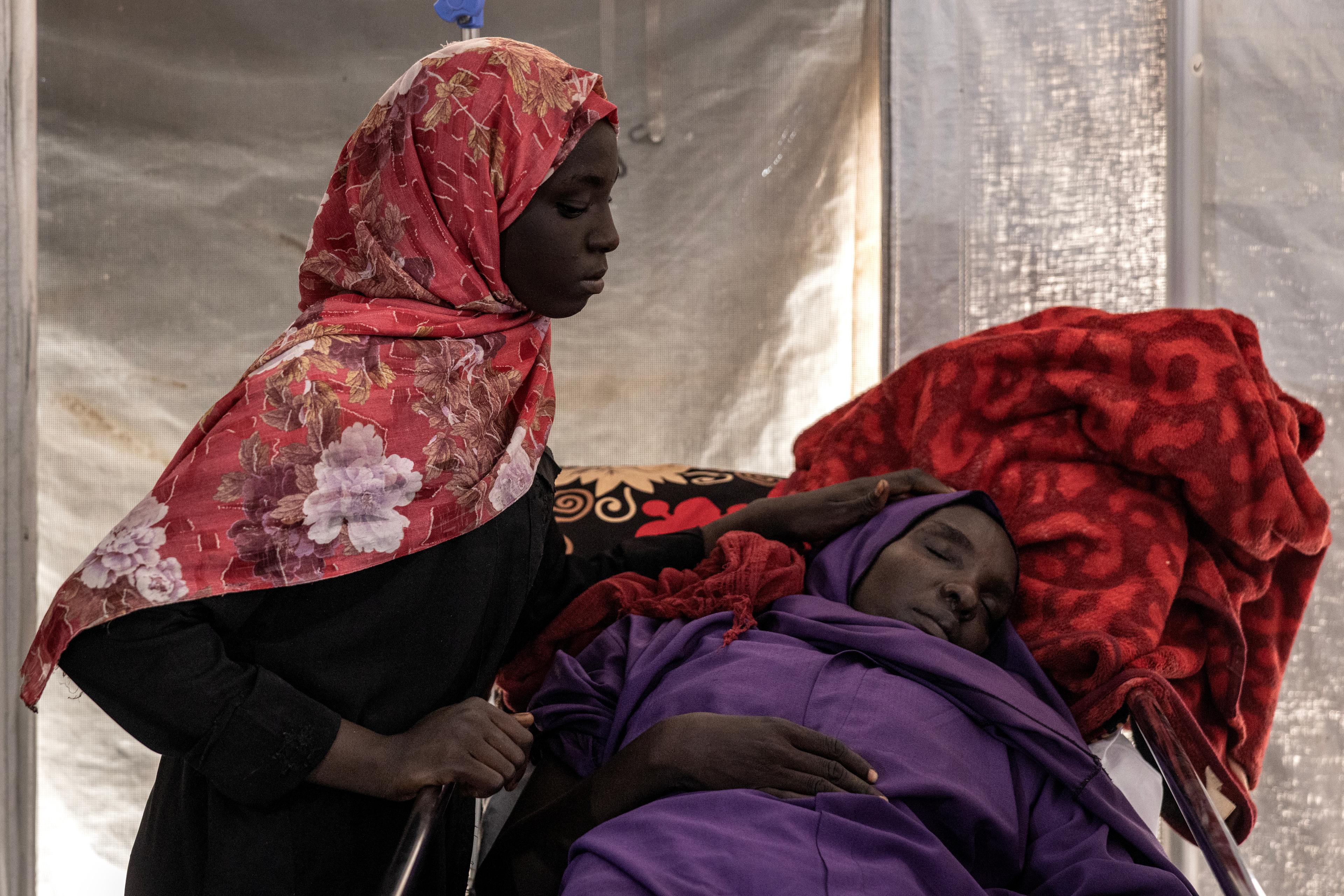 Sena Mahoobg, 16 ans (à gauche), réconforte sa mère, Amna Abdurahman, 35 ans, qui souffrait de fièvre et de gastro-entérite, aux urgences de l'hôpital MSF de Metche, dans l'est du Tchad, le 8 août 2024.