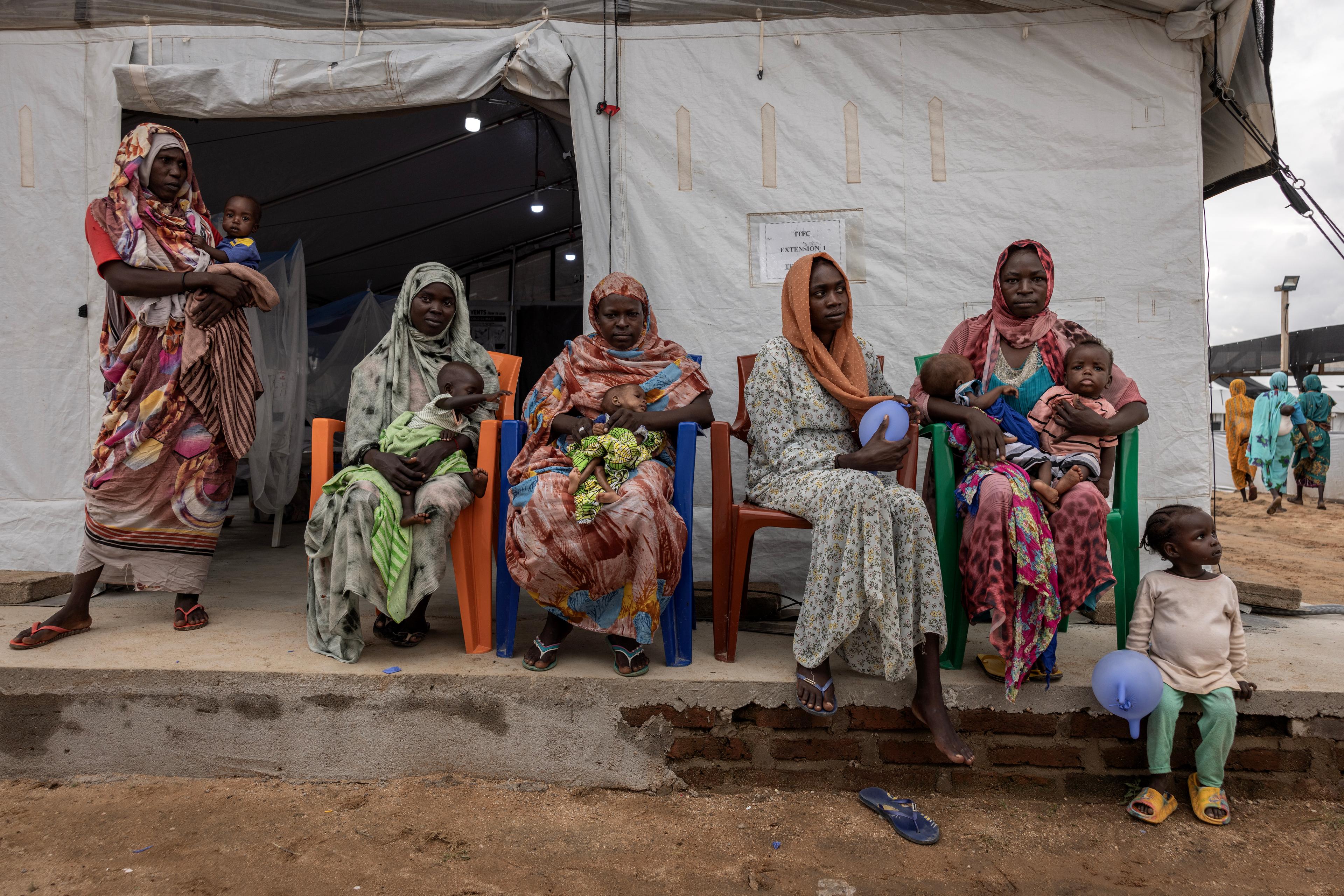 Des femmes sont assises à l'extérieur d'une tente pour l'alimentation thérapeutique d'enfants malnutris à l'hôpital MSF de Metche, dans l'est du Tchad, le 7 août 2024.