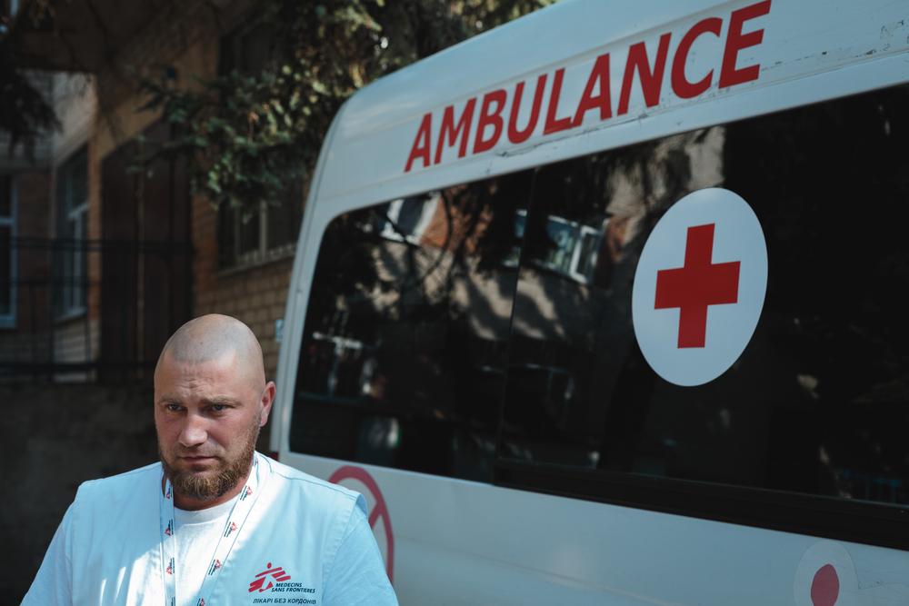 Dmytro Bilous, feldsher MSF, se tient à côté de l'ambulance MSF à l'extérieur de l'hôpital pour enfants de Sloviansk, qui est actuellement la base des ambulances.