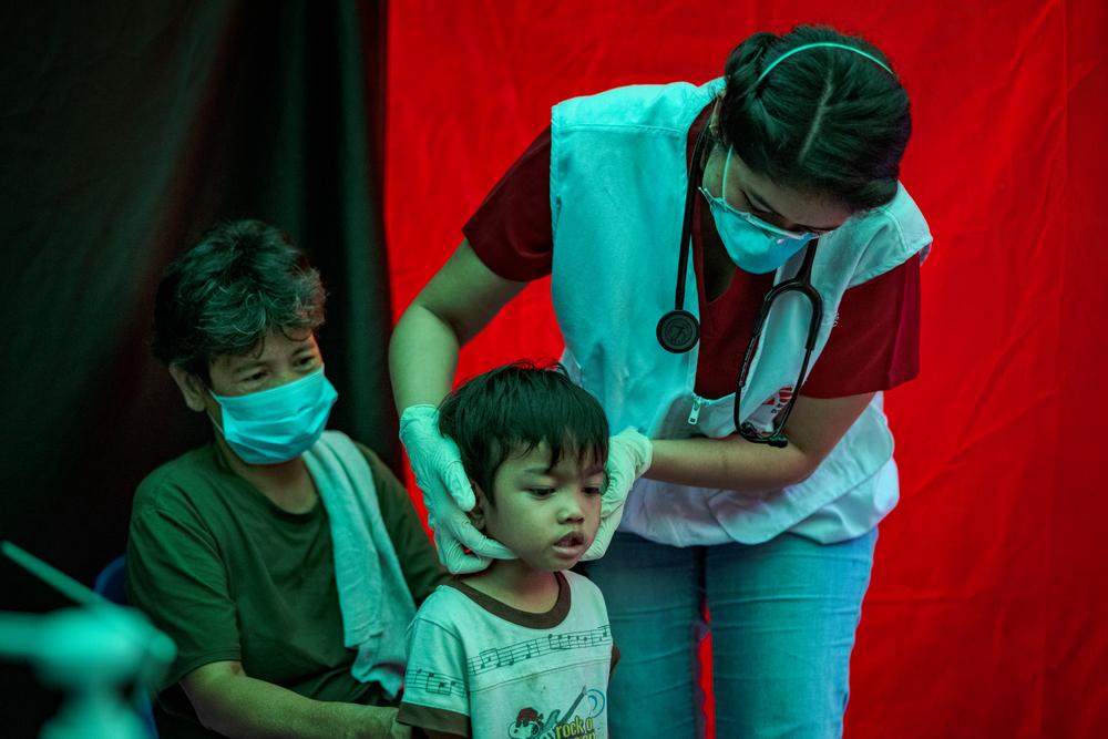 Agustina observe Trisha Thadhani, médecin tuberculeux de MSF, qui procède à l'évaluation médicale de son petit-fils Ion, dans l'un des sites de recherche active de cas de tuberculose de MSF, le 13 mars 2023 à Tondo, Manille, Philippines. © Ezra Acayan