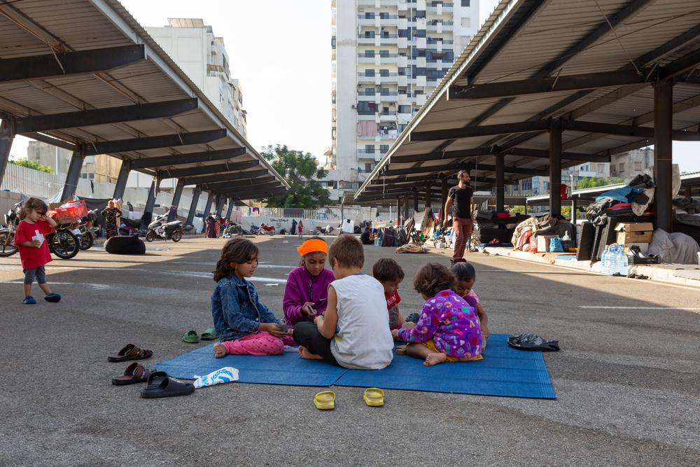 Des enfants réfugiés syriens sont assis sur un tapis dans un parking de la ville de Saïda, au sud du Liban, le mercredi 16 octobre 2024, où les réfugiés syriens, qui vivaient dans le sud du Liban, ont trouvé refuge après l'escalade israélienne au Liban.