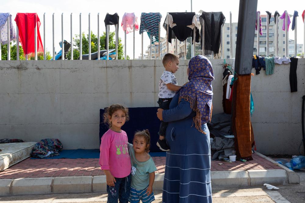 La réfugiée syrienne Hala, 24 ans, tient son fils Yamen, 2 ans, tandis que ses deux filles Razan, 6 ans, à gauche, et Rawan, 3,5 ans, se tiennent à côté d'elle, près du trottoir où elles dorment, dans un parking à Saida, au sud du Liban