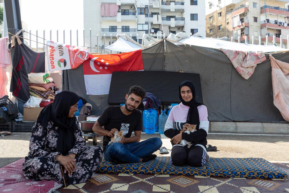 La réfugiée syrienne Shams, à gauche, est assise sur des matelas avec ses enfants Kazem, 20 ans, au centre, et Marimar, 14 ans, tenant leurs chatons dans un parking de la ville de Saida, au sud du Liban, le mercredi 16 octobre 2024.