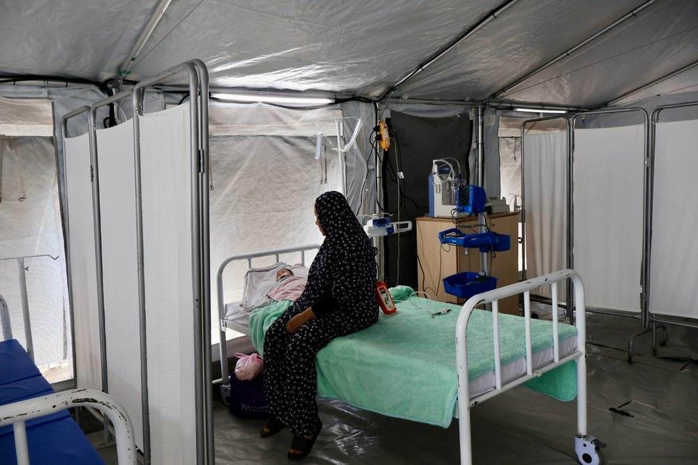 Faten, une mère de 39 ans, se tient debout à côté de son petit garçon qui souffre d’une grave infection respiratoire