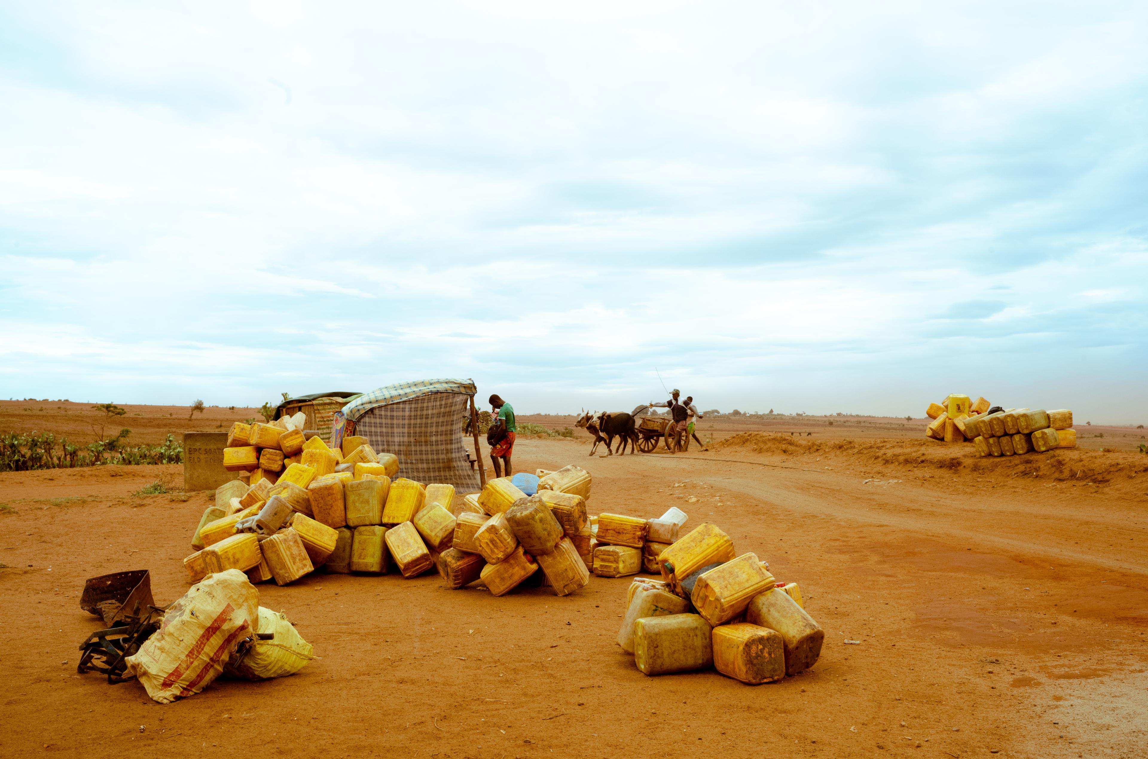 A un carrefour de la route nationale, des jerrycans vides attendent l'arrivée d'un camion-citerne pour approvisionner en eau les familles du quartier.