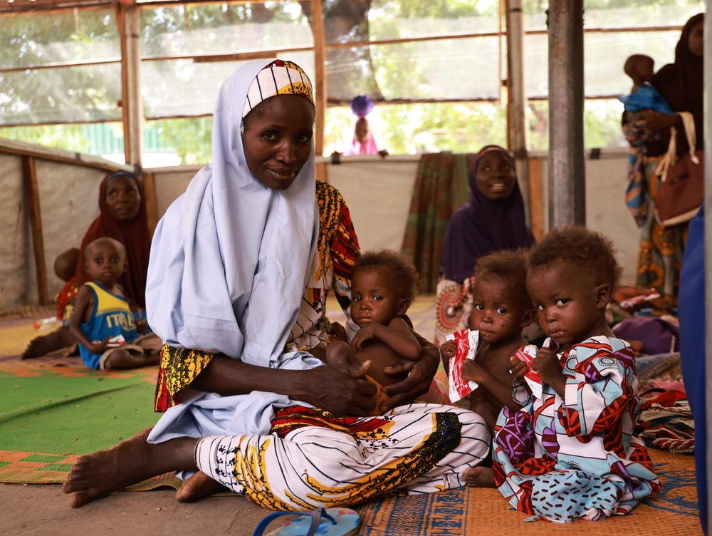 Nafisa Mutari s'assoit pour donner à ses triplés de 2 ans de la prunelle au centre thérapeutique d'alimentation ambulatoire Kofar Marusa, à Katsina, dans l'État de Katsina. Deux d'entre eux sont traités pour malnutrition.