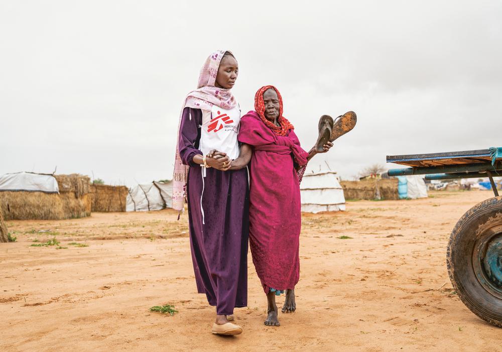 Aisha B. (28 ans), promotrice de santé, accompagne Aisha G., 80 ans, à la clinique MSF du camp de transit d'Adré, dans l'est du Tchad. ©Ante Bussmann/MSF