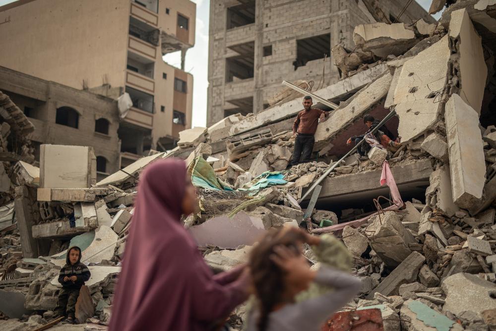 Une femme et ses enfants tentent de déterrer leurs affaires sous les décombres au carrefour Palestine, rue Naser, dans la ville de Gaza.