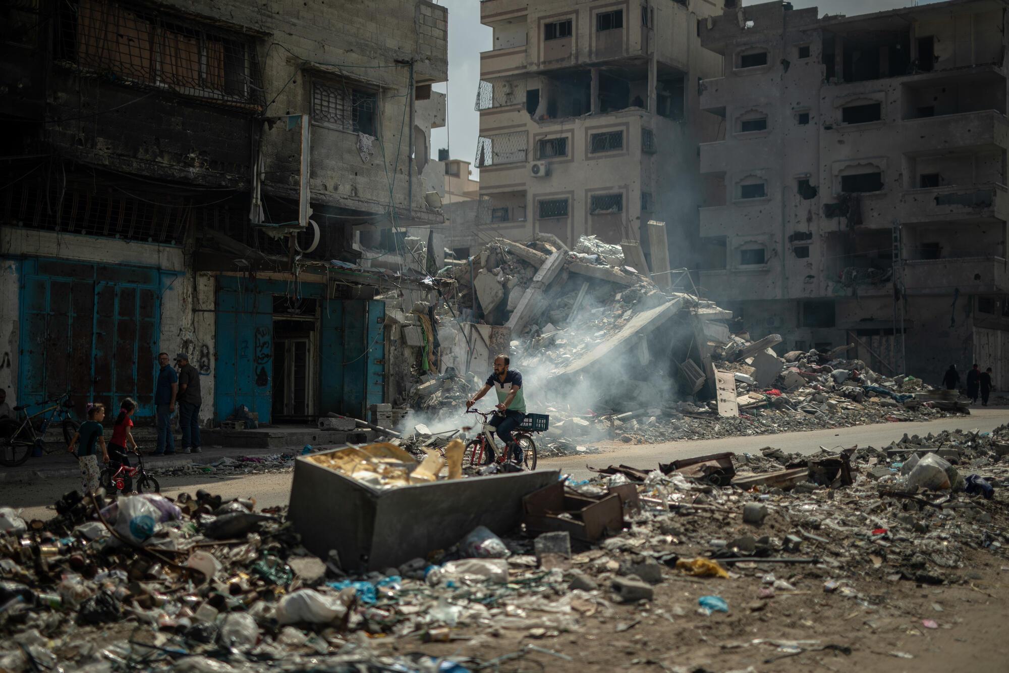 Dans le camp de réfugiés d'Al Shate', dans la ville de Gaza, un homme circule à vélo au milieu des destructions. © MSF