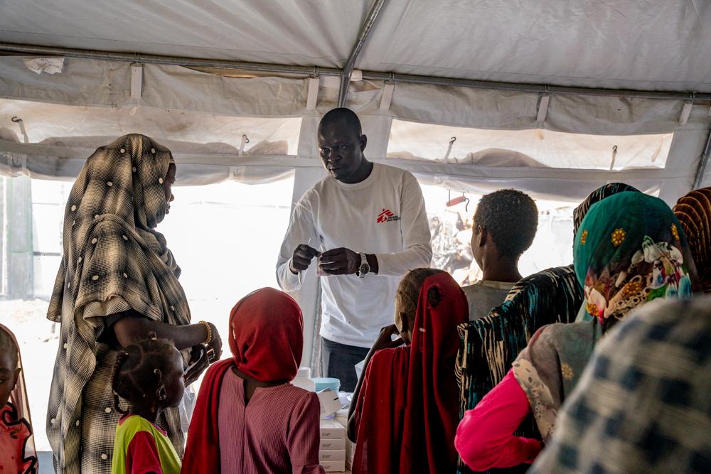 Une employée de MSF distribue les médicaments prescrits par les médecins de la clinique d'Atam. De nombreux patients font la queue pour recevoir leur tour.