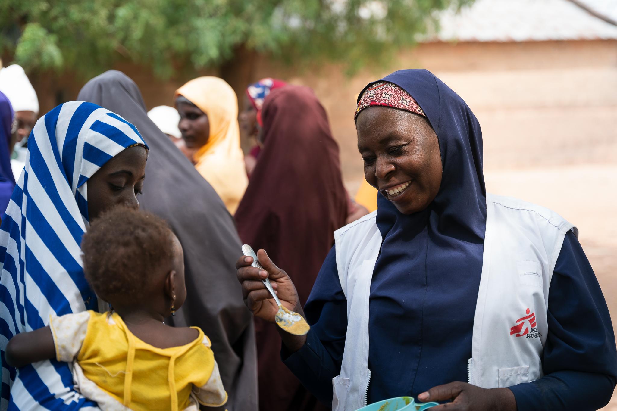 Maryam Muhammad, superviseure de promotion de la santé de MSF à Kebbi, donne une cuillère de Tom Brown à un enfant lors d'une démonstration de recette dans le village de Maishaka, dans l'État de Kebbi, au nord-ouest du Nigeria. Une centaine de femmes ont participé à cette démonstration.