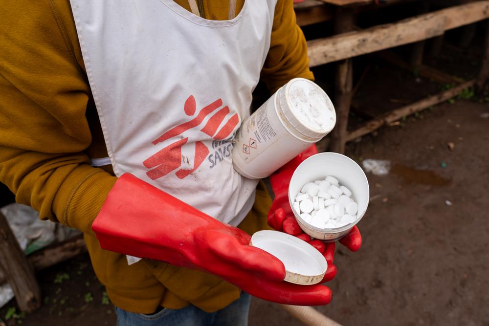 Un employé de MSF montre des comprimés de purification utilisés pour fournir de l'eau propre à la population de Lomera, une ville minière du Sud-Kivu aux prises avec une épidémie de choléra. RDC, juin, 2025 © Sam Bradpiece/MSF 