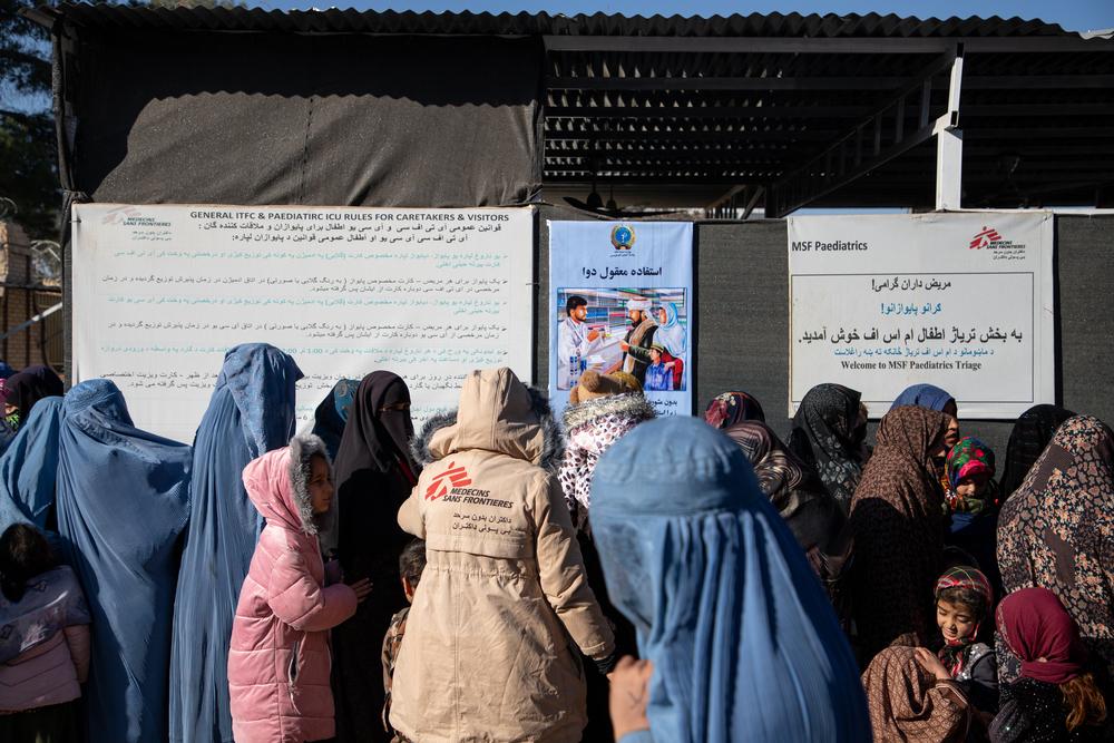 Des mères et leurs enfants font la queue devant la salle de triage pour que leurs enfants soient examinés par le personnel médical. 