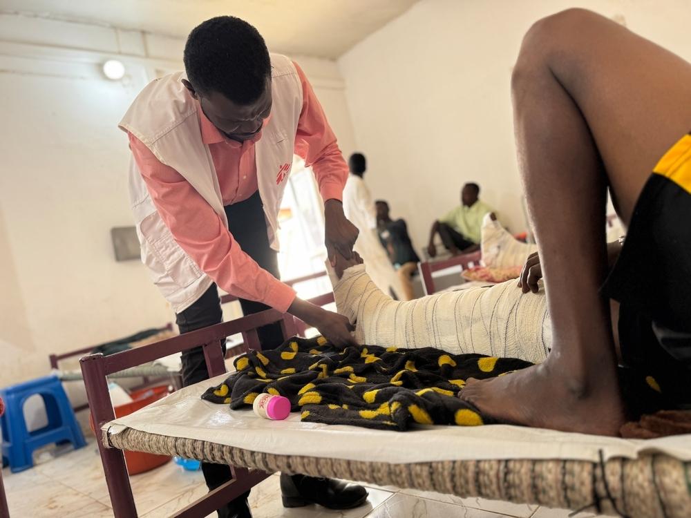 Le Dr Abubaker Abdalla, responsable des activités médicales, réajuste le pansement d'un patient blessé par balle, dans ce qui était autrefois la salle d'isolement de l'hôpital de Tawila