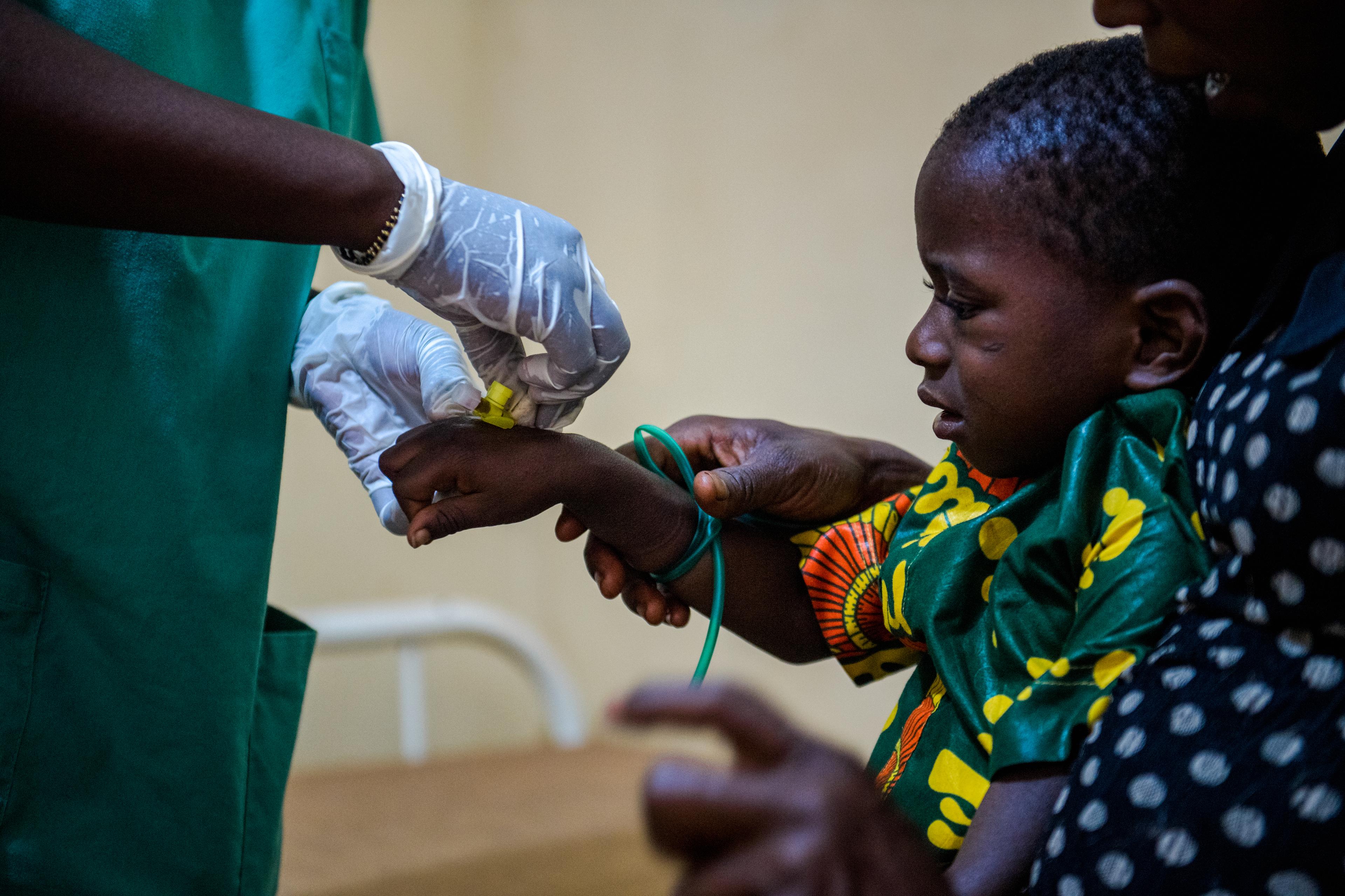 Toure Djenabou, une infirmière, insère un tube intraveineux dans la main d'un enfant en Guinée.