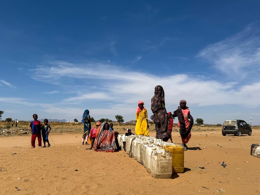 Les personnes déplacées d'El Fasher attendent leur tour avec des jerricans pour aller chercher de l'eau une fois les camions arrivés.