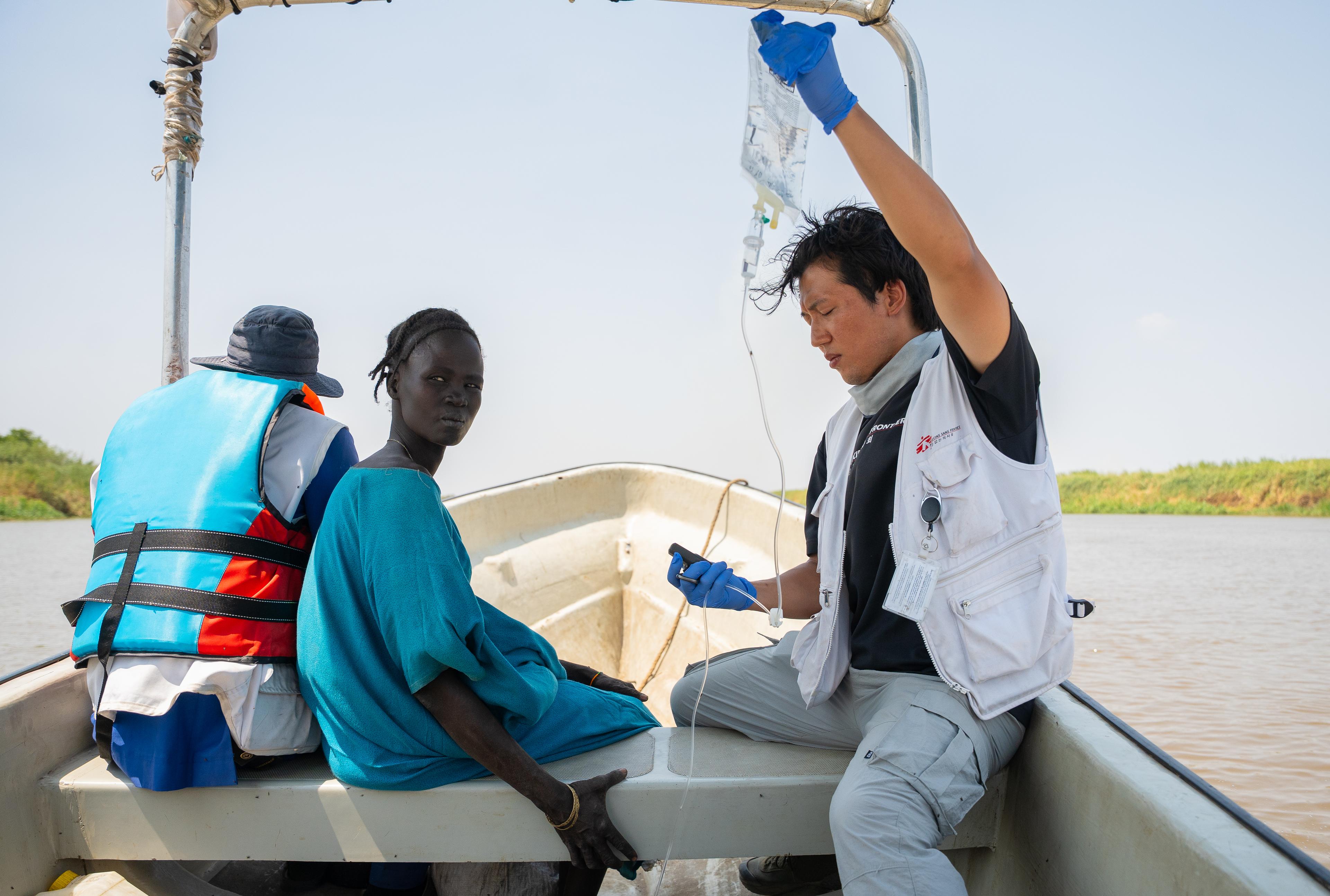 Joon Hyun, membre du personnel de MSF, tient une perfusion intraveineuse pour un patient orienté vers le centre de soins de santé primaires de Chuil, alors que le patient est transporté pour recevoir des soins complémentaires depuis une clinique mobile à Yakuach, Soudan du Sud 