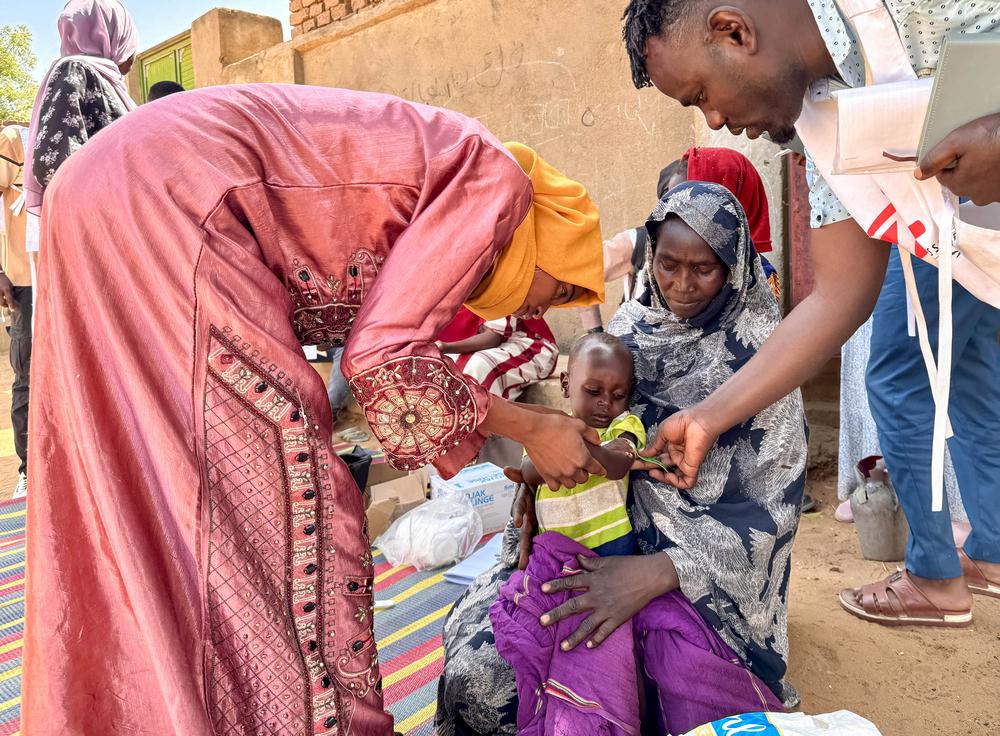 Un bénévole local et un membre du personnel de MSF procèdent à un dépistage par mesure du périmètre brachial (MUAC) sur Mohamed Ayoub, âgé de 18 mois, immédiatement après sa vaccination contre la rougeole. À l’issue de ce dépistage, Mohamed a été orienté vers un centre de santé spécialisé afin d’entamer un traitement contre la malnutrition. Souda, janvier 2026 © Cindy Gonzalez/MSF 