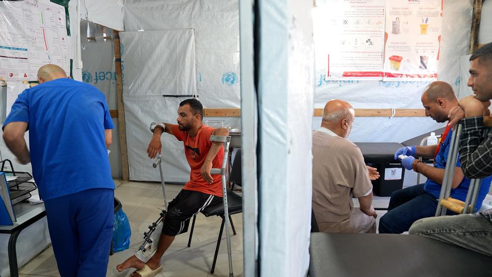 Un membre du personnel de MSF examine la blessure de Saad Hussein, contraint de vivre avec un fixateur externe depuis qu'il a été blessé en 2025 lors d'une distribution alimentaire organisée par la Fondation humanitaire de Gaza. Centre de soins de santé primaires Al Mawasi, Khan Younis, Gaza. Mai, 2026 © Nour Alsaqqa/MSF 