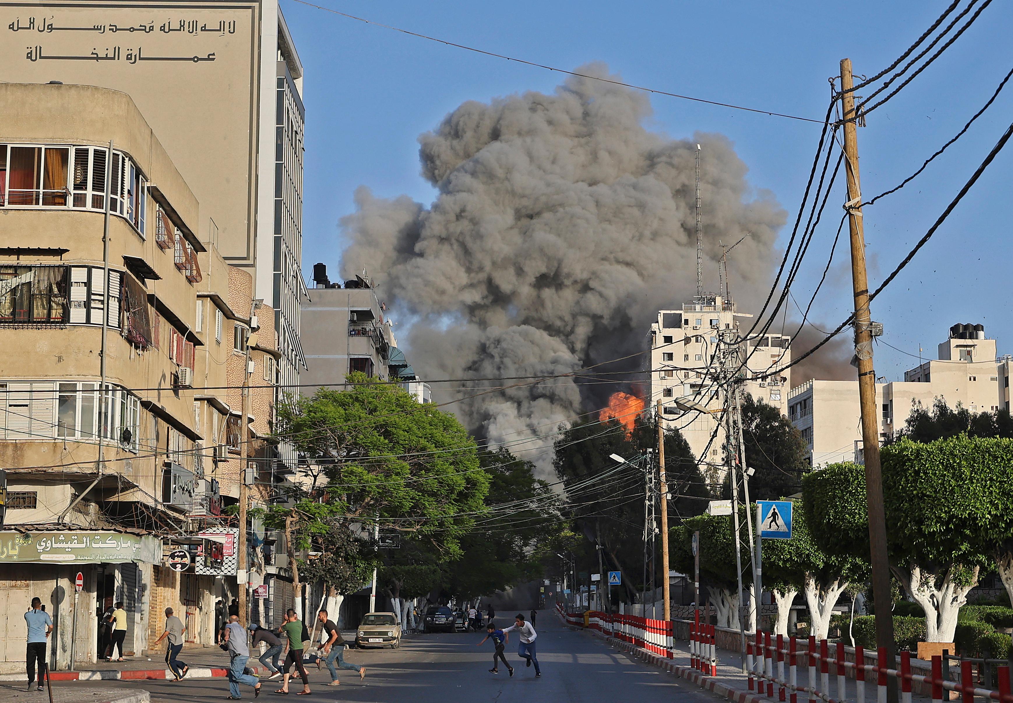 Des personnes s&#039;enfuient des environs de la tour Al-Sharouk alors qu&#039;elle s&#039;effondre après avoir été touchée par une frappe aérienne israélienne, à Gaza, le 12 mai 2021. 