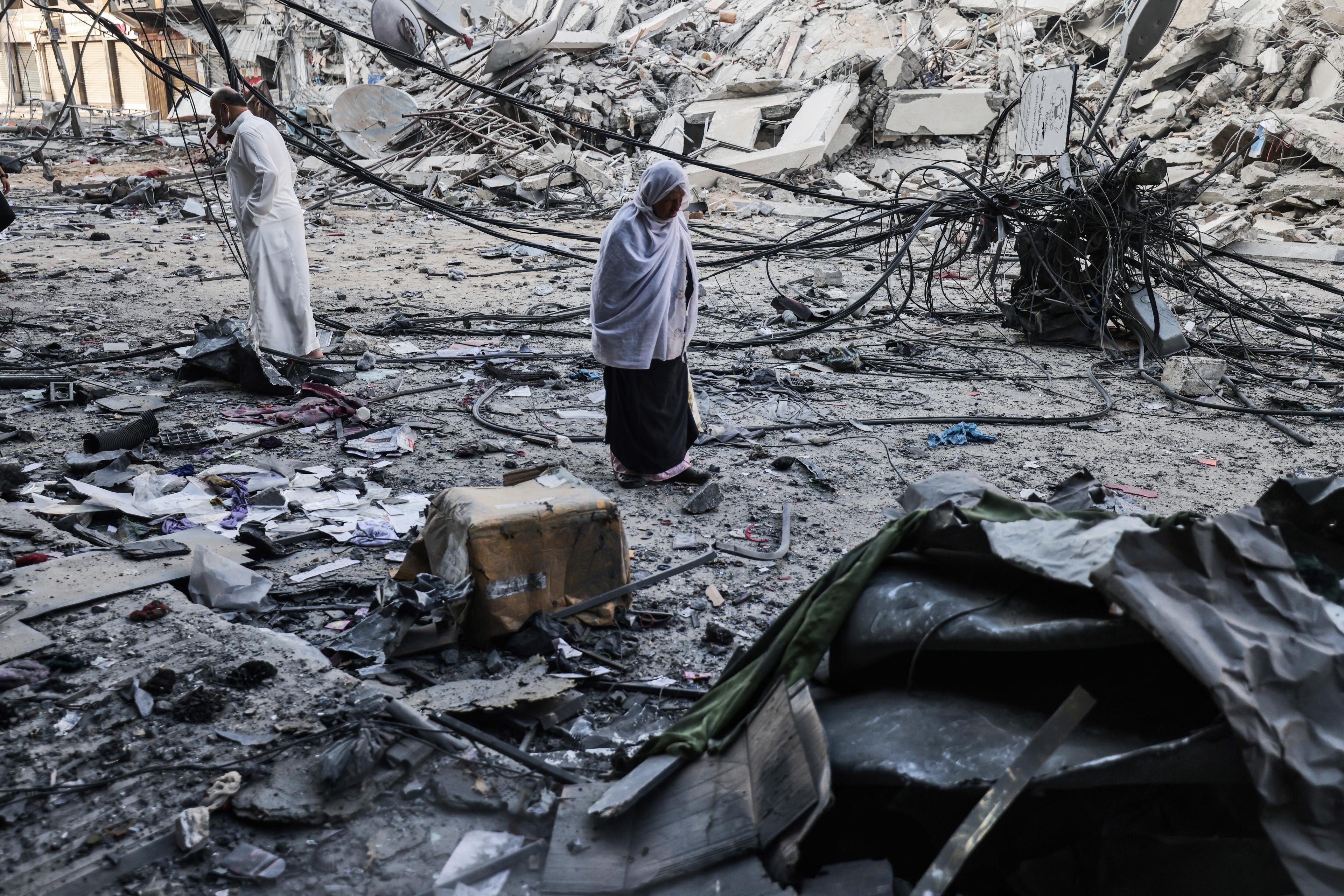 Des Palestiniens marchent au milieu des débris près de la tour al-Sharouk, après sa destruction par une frappe aérienne israélienne, dans la ville de Gaza, le 13 mai 2021. 