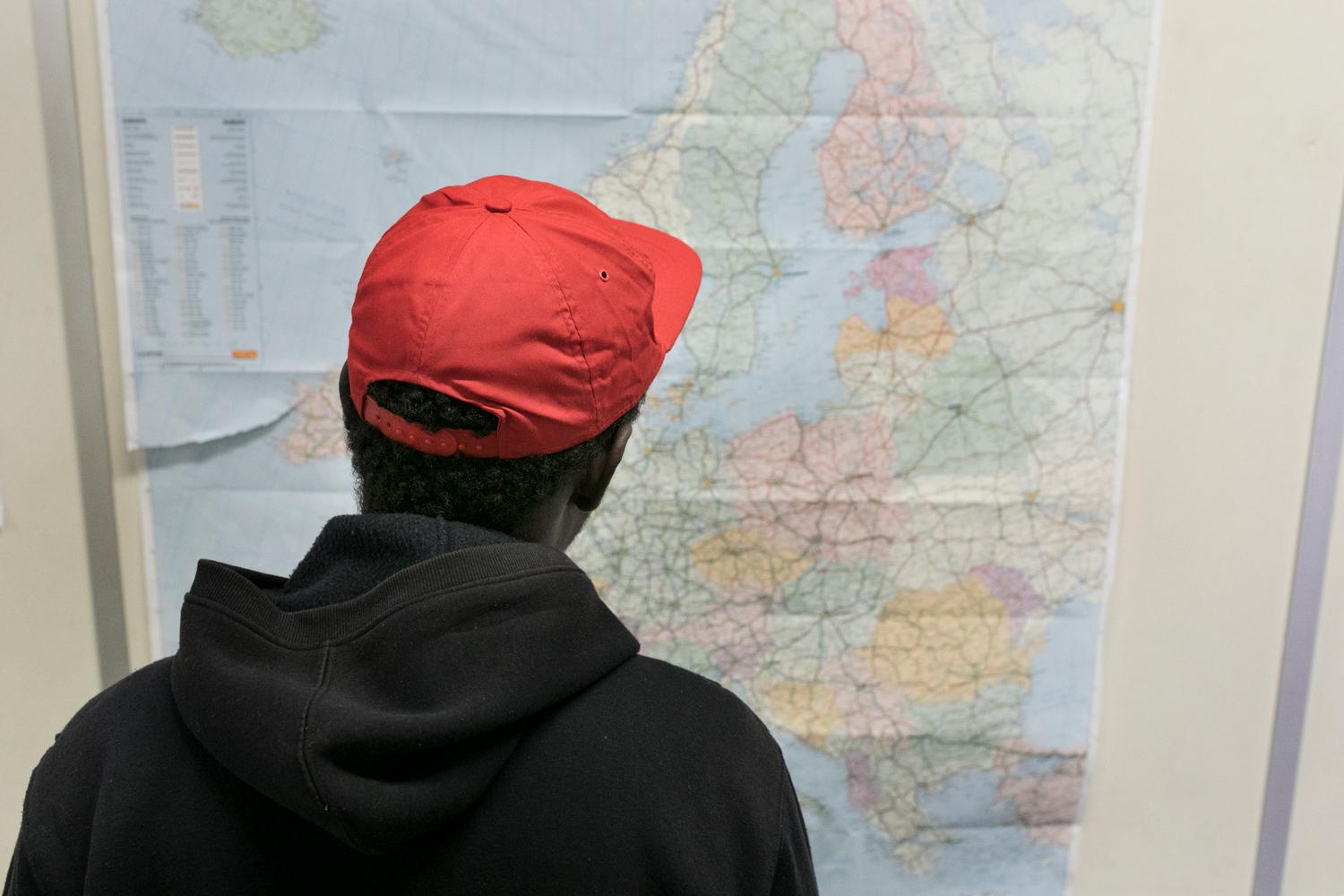  Un jeune migrant consulte une carte de l&#039;Europe dans le « hub humanitaire » à Bruxelles. Août 2018. 