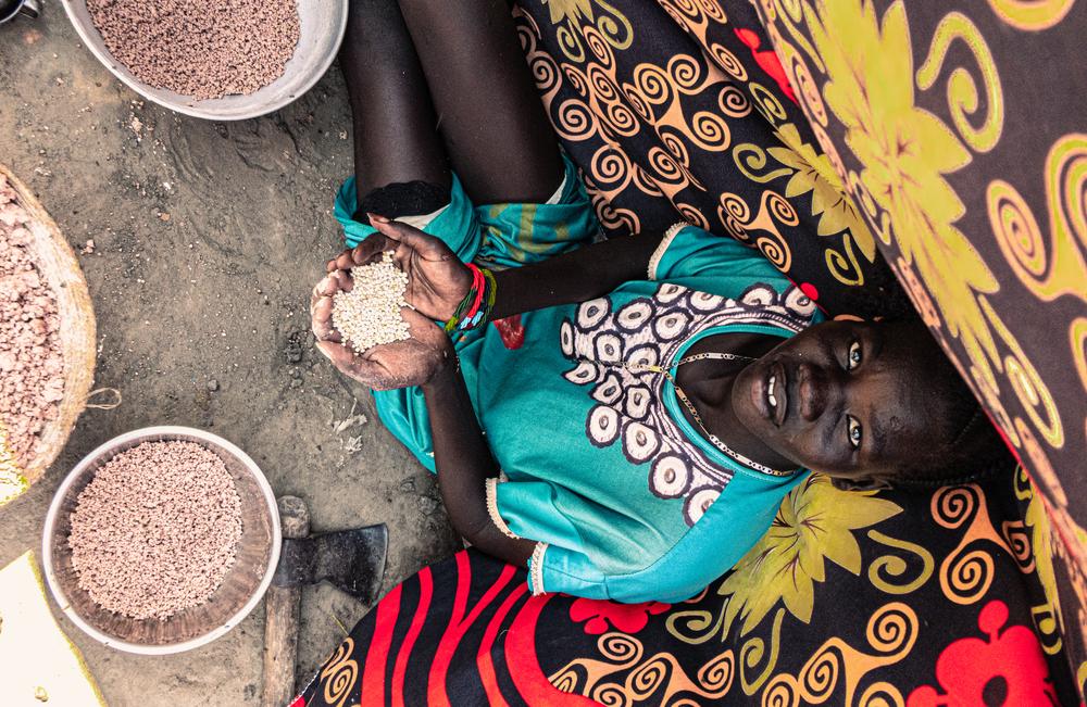 A young woman sorts grain in her shelter in the town of Bentiu, Unity State. 