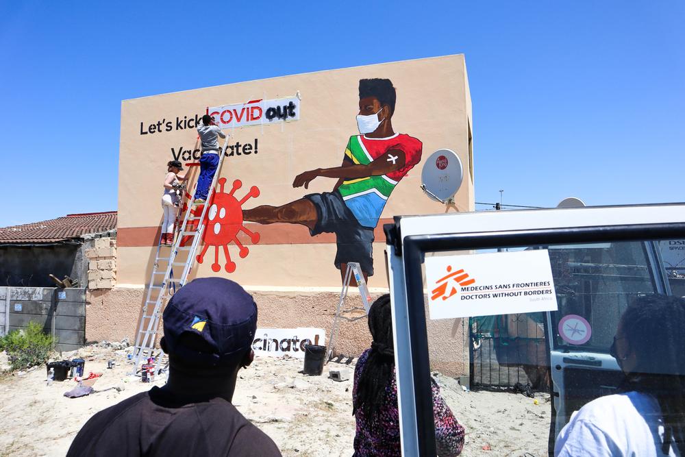 Les membres de la communauté regardent la peinture murale. 