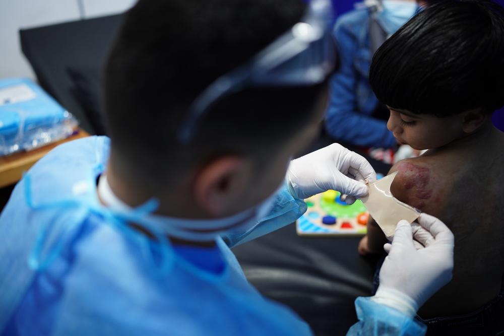 An MSF physical therapist Salama Abu Deheleh prepares an additional layer of dressing for a 3-year-old patient Wadi to control a scar formation on Wadi’s shoulder.