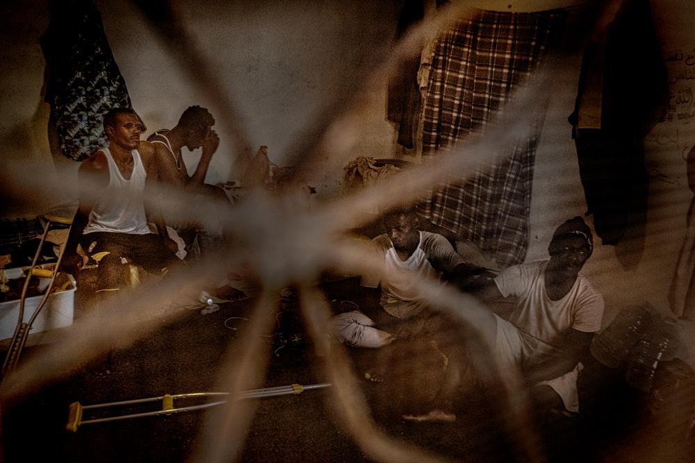 "We sit, we wait and we're scared". A group of migrants and refugees gathered together in a shared dwelling in Libya in August 2021. 