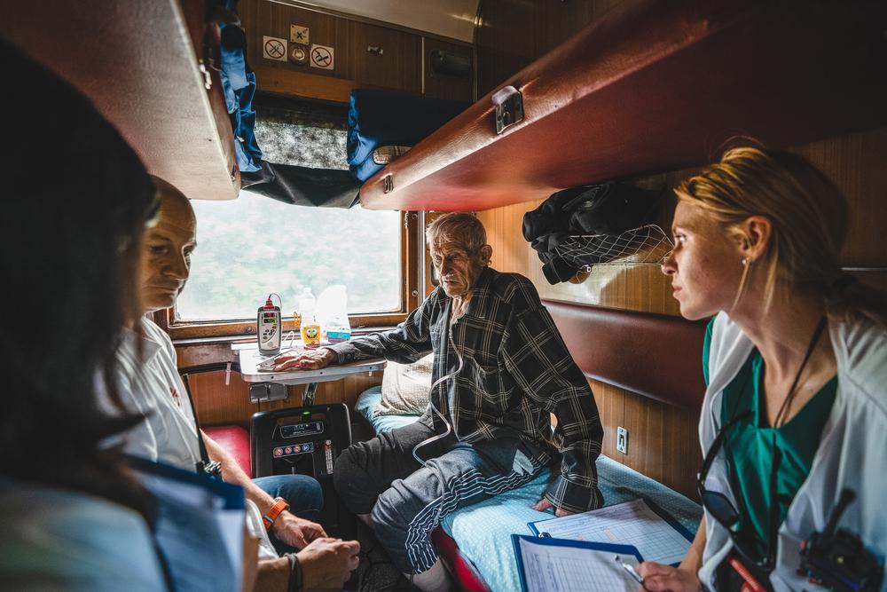 L&#039;équipe médicale à bord du train médical de MSF discute de l&#039;état d&#039;un patient âgé blessé par la guerre pendant le voyage de Pokrovsk à Lviv. 