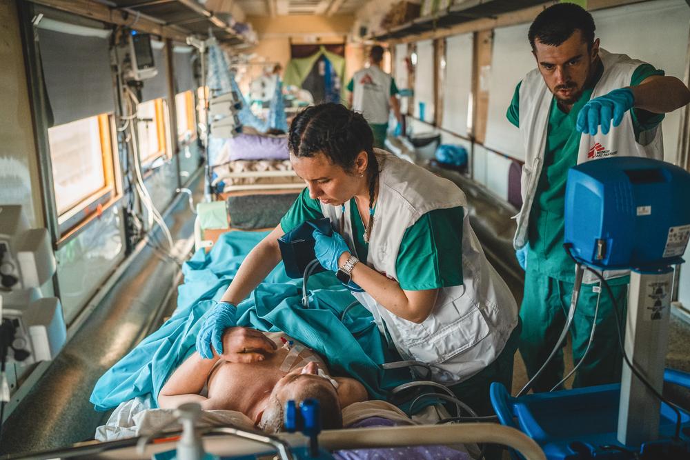 L'équipe médicale à l'intérieur de l'unité de soins intensifs du train médical de MSF surveille et stabilise un patient gravement blessé par la guerre pendant le voyage de Pokrovsk à Lviv. 