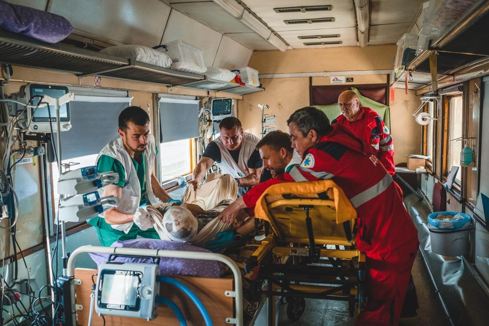 Un patient gravement blessé par la guerre est déplacé d&#039;un brancard d&#039;ambulance à un lit dans l&#039;unité de soins intensifsdu train médicalisé de MSF. 
