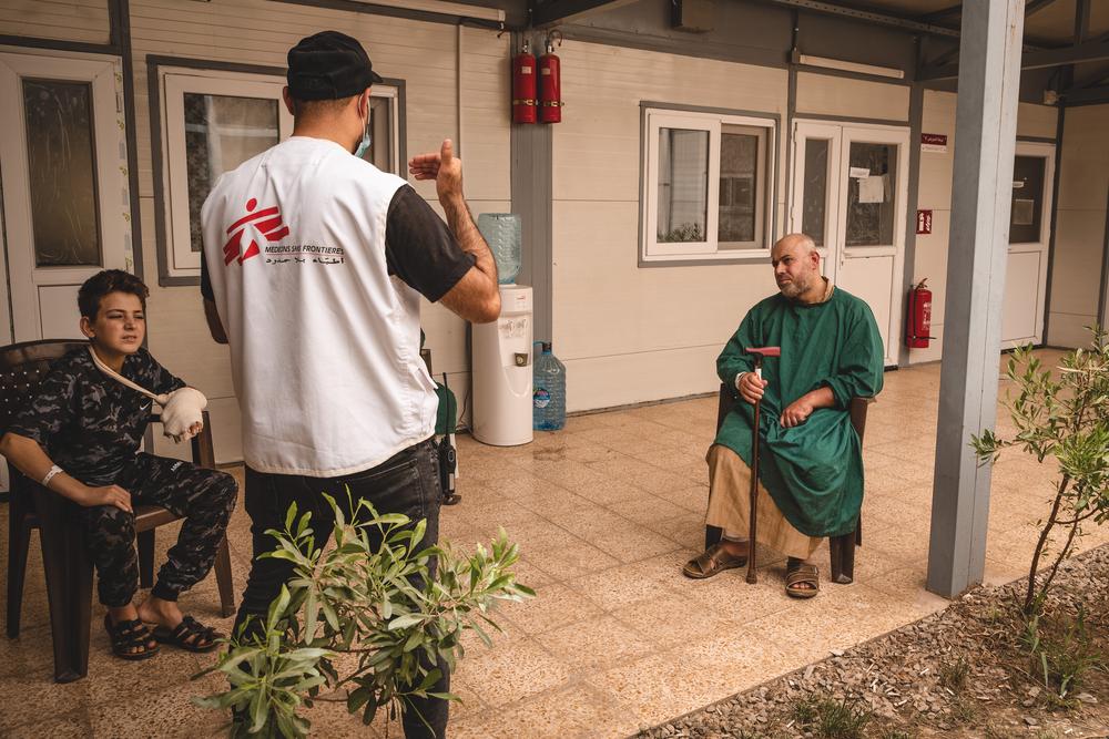 Health education session in the yard of the MSF-run Al-Wahda Hospital, East Mosul. Karam Yassine, health promoter explains to Faris the best practices to avoid infections and complications after surgery. 