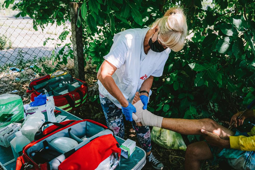 Une infirmière MSF attache la cheville d&#039;un patient lors d&#039;une consultation médicale de la clinique mobile MSF dans la zone frontalière de Horgos 2 en Serbie. 