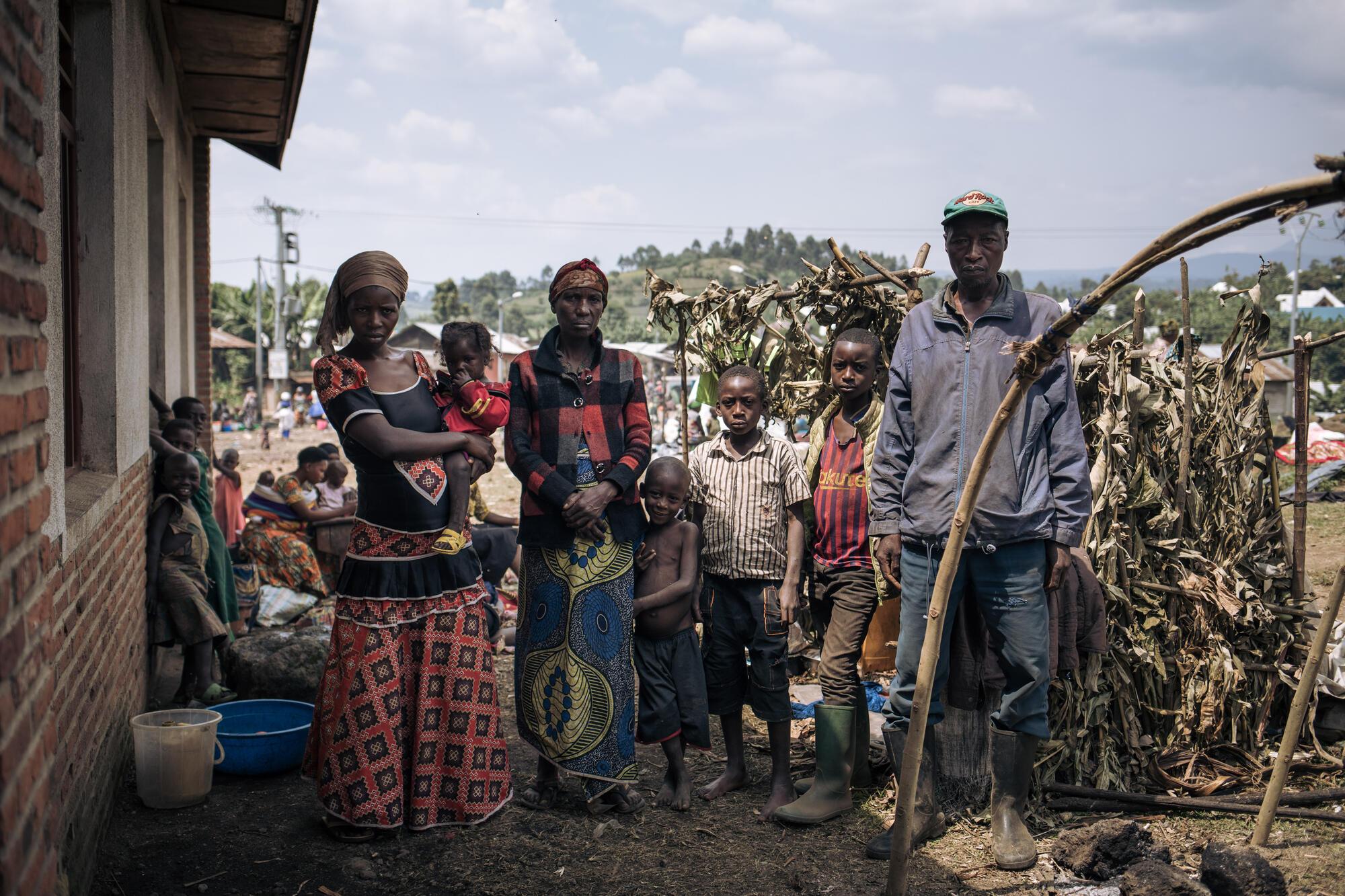 Ponsie, un déplacé de 54 ans, pose avec sa famille pour une photo devant l&#039;abri qu&#039;il a construit à côté de l&#039;école primaire de Rumangabo.  