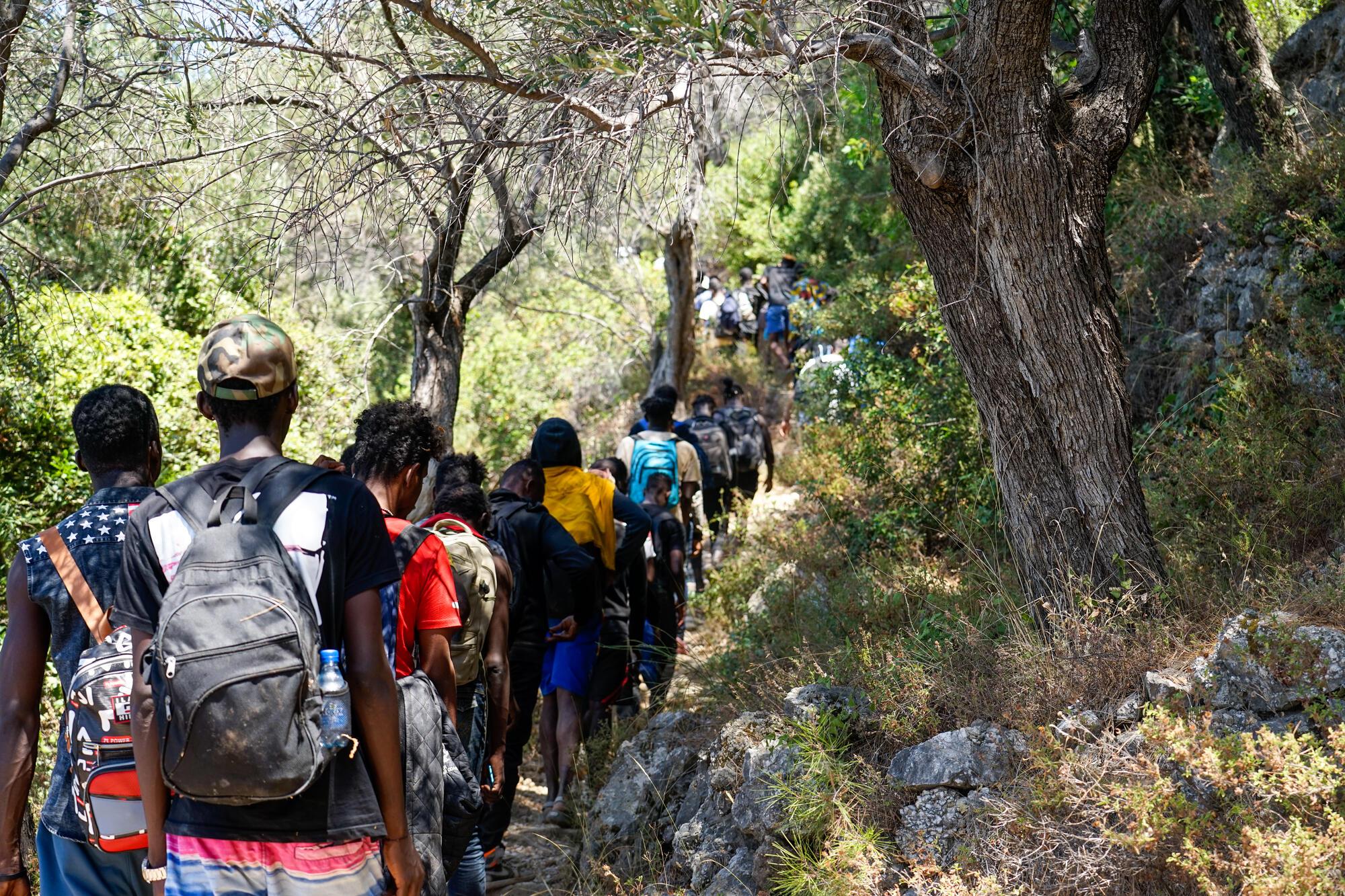 Des personnes tout juste arrivées sur l&#039;île de Samos, en Grèce, marchent sur un chemin rocheux. 